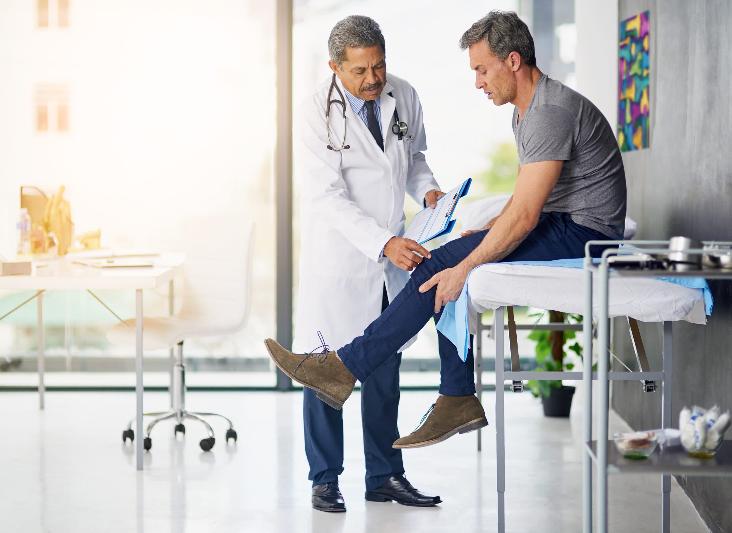 A clinician examining a patient’s knee in a consultation room