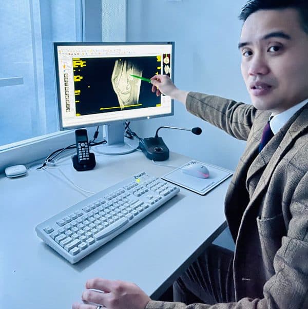 A specialist reviewing a knee scan on screen with a patient
